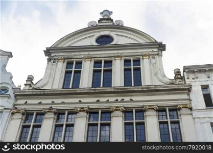 Looking up at old building with gilding, gable, windows, and pigeon. Grand Place, Brussels, Belgium, Europe.