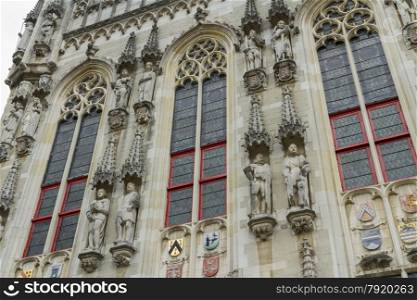 Looking up at statues and windows of Town Hall or Stadhuis. Burg Square, Bruges, West Flanders, Belgium, Europe