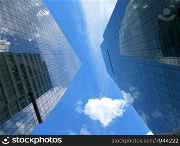 Looking up at two skyscrapers with blue sky