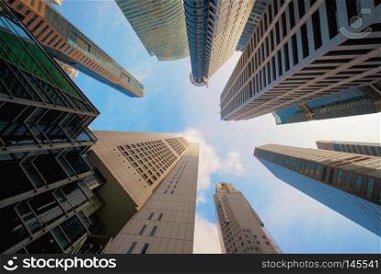 Looking up high-rise buildings, skyscrapers, architectures in smart city for technology background in Singapore City with blue sky