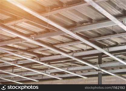 Looking up structure of steel roof frame with iron beams and gray tile roof in construction site.