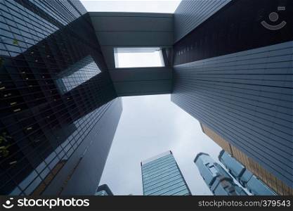 Looking up to high-rise buildings, skyscrapers, architectures in smart city for business and technology background in Hong Kong City with blue sky