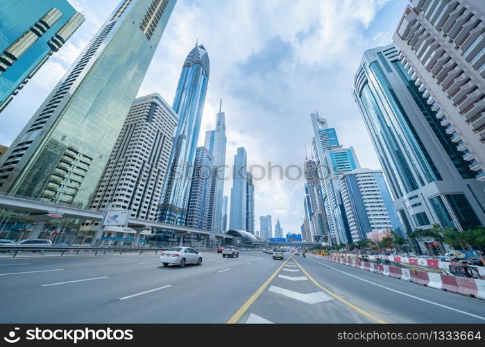 Looking up to high-rise office buildings, skyscrapers, architectures in financial district with blue sky. Smart urban city for business and technology concept background in Downtown Dubai, UAE.