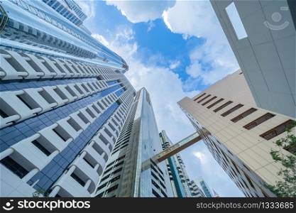 Looking up to high-rise office buildings, skyscrapers, architectures in financial district with blue sky. Smart urban city for business and technology concept background in Downtown Dubai, UAE.