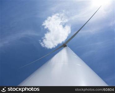 looking up to wind turbine and blue sky with one cloud