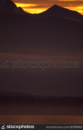 Looming Mountains Silhouetted By A Golden Sunset