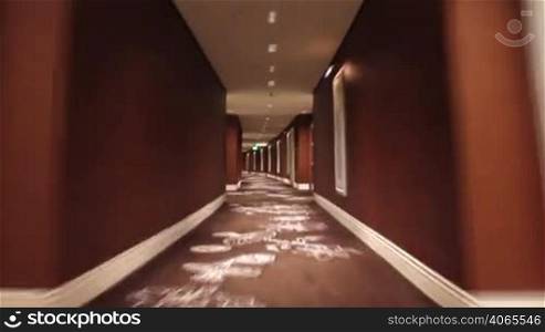 Looping shot, moving quickly through a long curved hotel hallway.