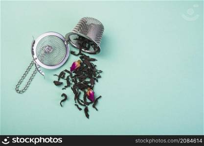 loose dried tea herbs spilled from tea strainer against colored backdrop