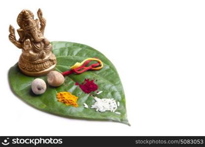 Lord Ganesha idol placed on Betel Leaf with Rice,Areca nut,Red thread,Kumkum and Turmeric