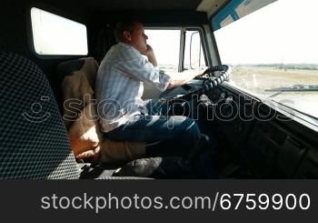 Lorry driver talking on the cell phone at the wheel of truck