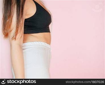 Lose belly fat concept from close up woman in sportswear with hand holding her own belly fat and cellulite.