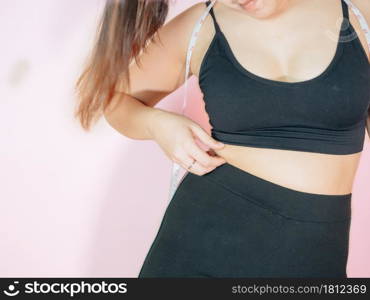 Lose belly fat concept from close up woman in sportswear with hand holding her own belly fat and cellulite.