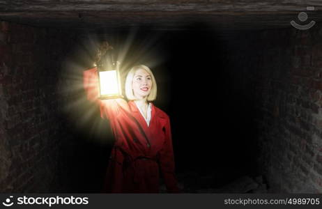 Lost in night. Young blond woman in red cloak with lantern