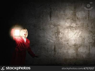 Lost in night. Young scared woman in red cloak with lantern