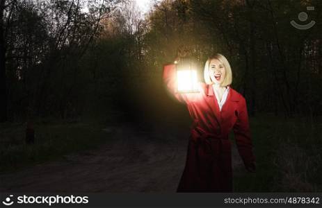 Lost in night. Young woman in red cloak with lantern lost in forest