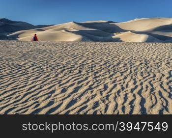 Lost in the sea of sand - a lonely hiker in a dunefield in Great Sand Dunes National Park, Colorado