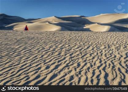 Lost in the sea of sand - a lonely hiker in a dunefield in Great Sand Dunes National Park, Colorado