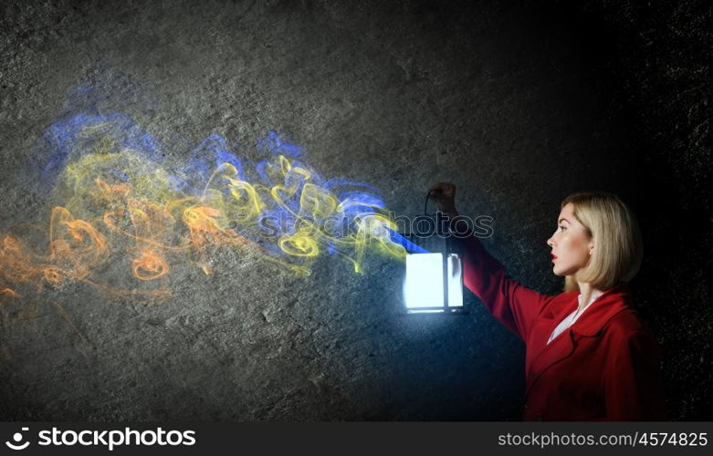 Lost woman. Young blonde in red cloak with lantern in darkness