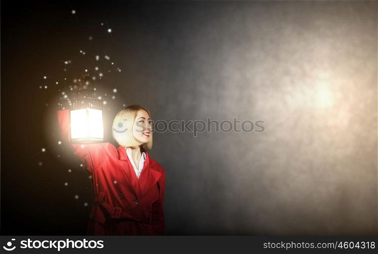 Lost woman. Young blonde in red cloak with lantern in darkness