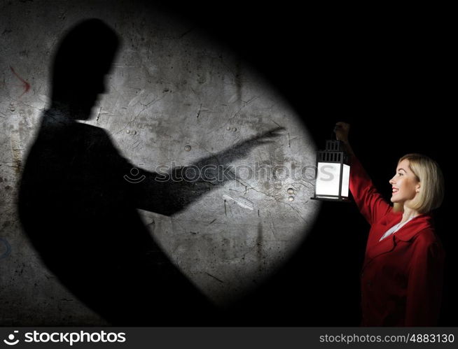 Lost woman. Young blonde in red cloak with lantern in darkness