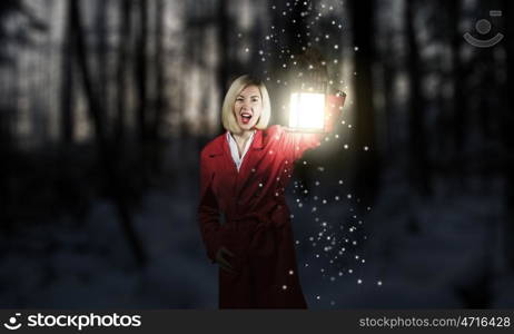 Lost woman. Young blonde in red cloak with lantern in night forest