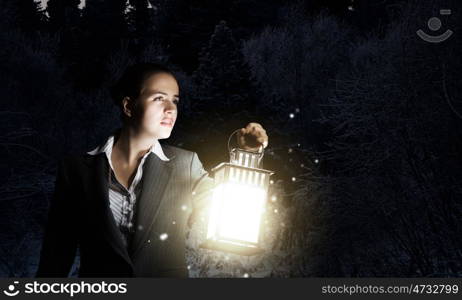 Lost woman. Young pretty businesswoman with lantern in darkness