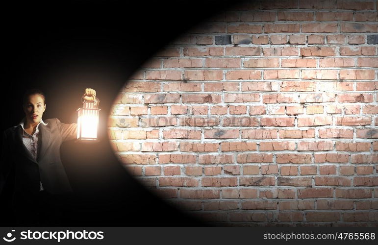 Lost woman. Young pretty businesswoman with lantern in darkness