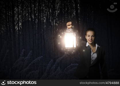 Lost woman. Young pretty businesswoman with lantern in darkness