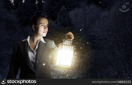 Lost woman. Young pretty businesswoman with lantern in darkness