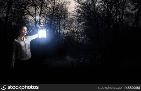 Lost woman. Young pretty businesswoman with lantern in darkness