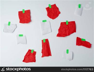 lot of torn red and white pieces of paper glued with green scotch tape on a white background, place for text