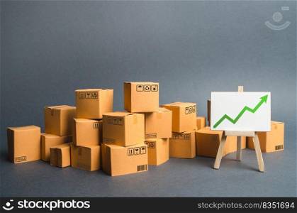 Lots of cardboard boxes and a stand with a green up arrow. rate growth of production of goods and products, increasing economic indicators. Increasing consumer demand, increasing exports or imports.