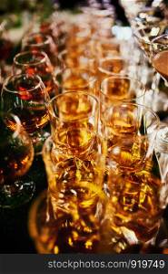 lots of glasses of whiskey. glasses of whiskey or brandy. alcohol. selective focus.