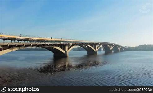 lots of metro trains on bridge ride over Dnipro river at sunny day, timelapse