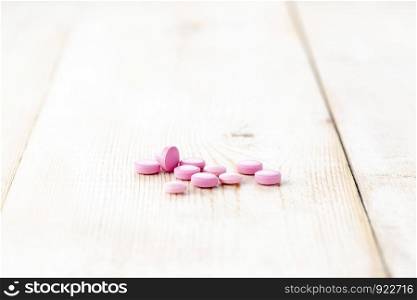 Lots of round pink pills. Close-up, wooden table. Lots of round pink pills. Close-up, wooden background