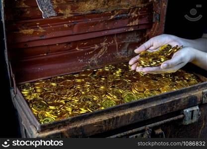Lots of stacking Gold Coin in lady hand and treasure chest at black background