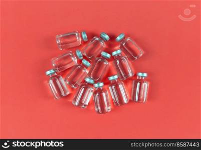 Lots of vials with liquid medicine on a red backdrop.. Lots of vials with liquid medicine on red backdrop.