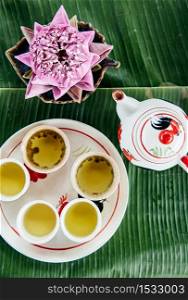 Lotus stamen or lotus pollen tea set. Thai Asian herbal flower tea seving in ceramic cups and pot on banana leaves. Top view