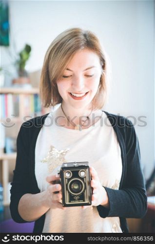 Loughing girl is making a picture with a vintage camera