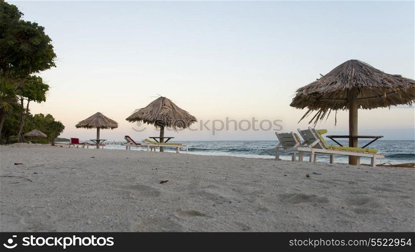 Lounge chairs with sunshades on the beach, Bay Islands, Honduras
