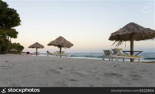 Lounge chairs with sunshades on the beach, Bay Islands, Honduras