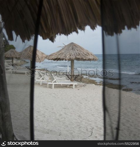 Lounge chairs with sunshades on the beach, Utopia Village, Utila Island, Bay Islands, Honduras