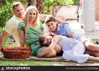 Lovable family of four relaxing during sunny day and looking at camera