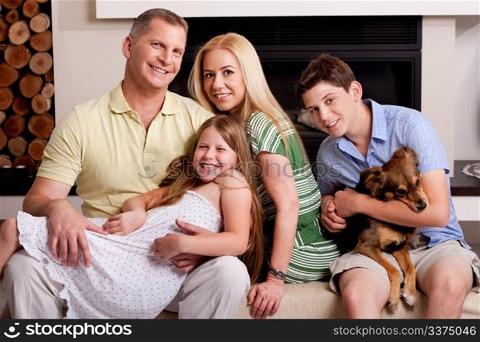 Lovable family poisng in living room as young boy holds little puppy in his arms
