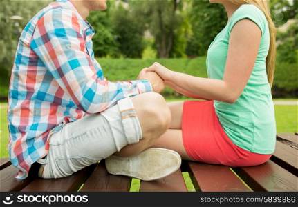 love, affection, feelings and people concept - close up of happy couple holding hands in park