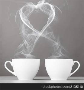 love and coffee. heart silhouette from steaming hot coffee cups