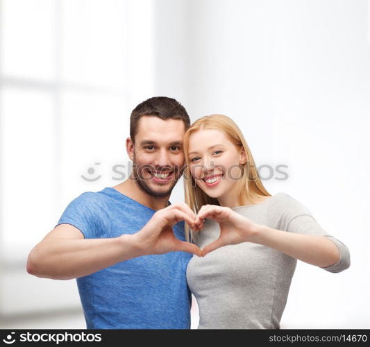 love and family concept - smiling couple showing heart with hands