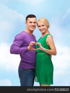 love and family concept - smiling couple showing heart with hands