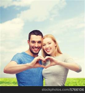 love and family concept - smiling couple showing heart with hands