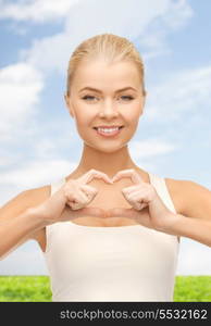 love and gesture concept - smiling woman showing heart shape gesture